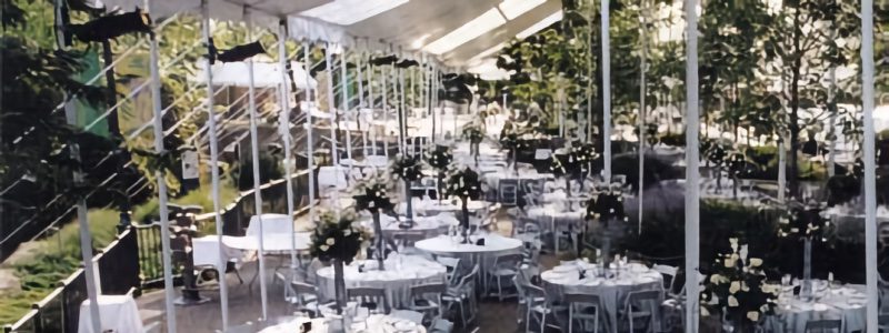 An event space at the zoo decorated with white floral arrangements and table settings.